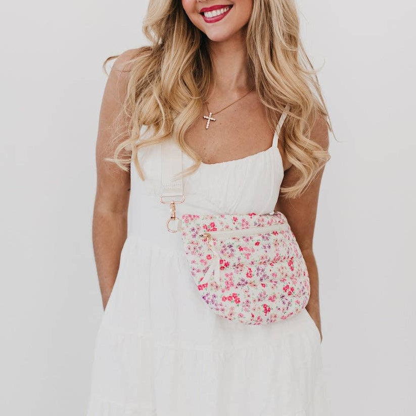 Woman wearing a white dress with a floral skirt against a plain background