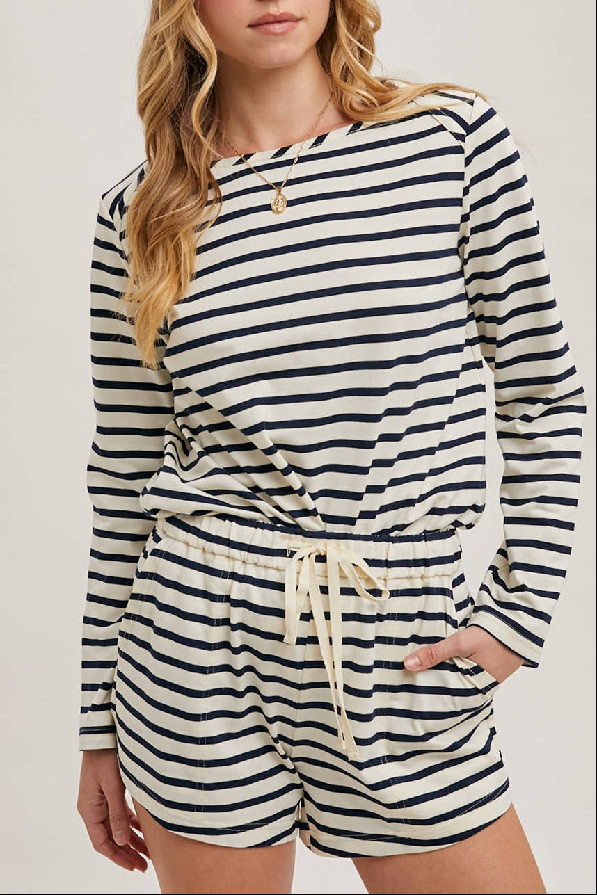 Woman wearing a navy and white striped longsleeve shirt and short set on a plain background