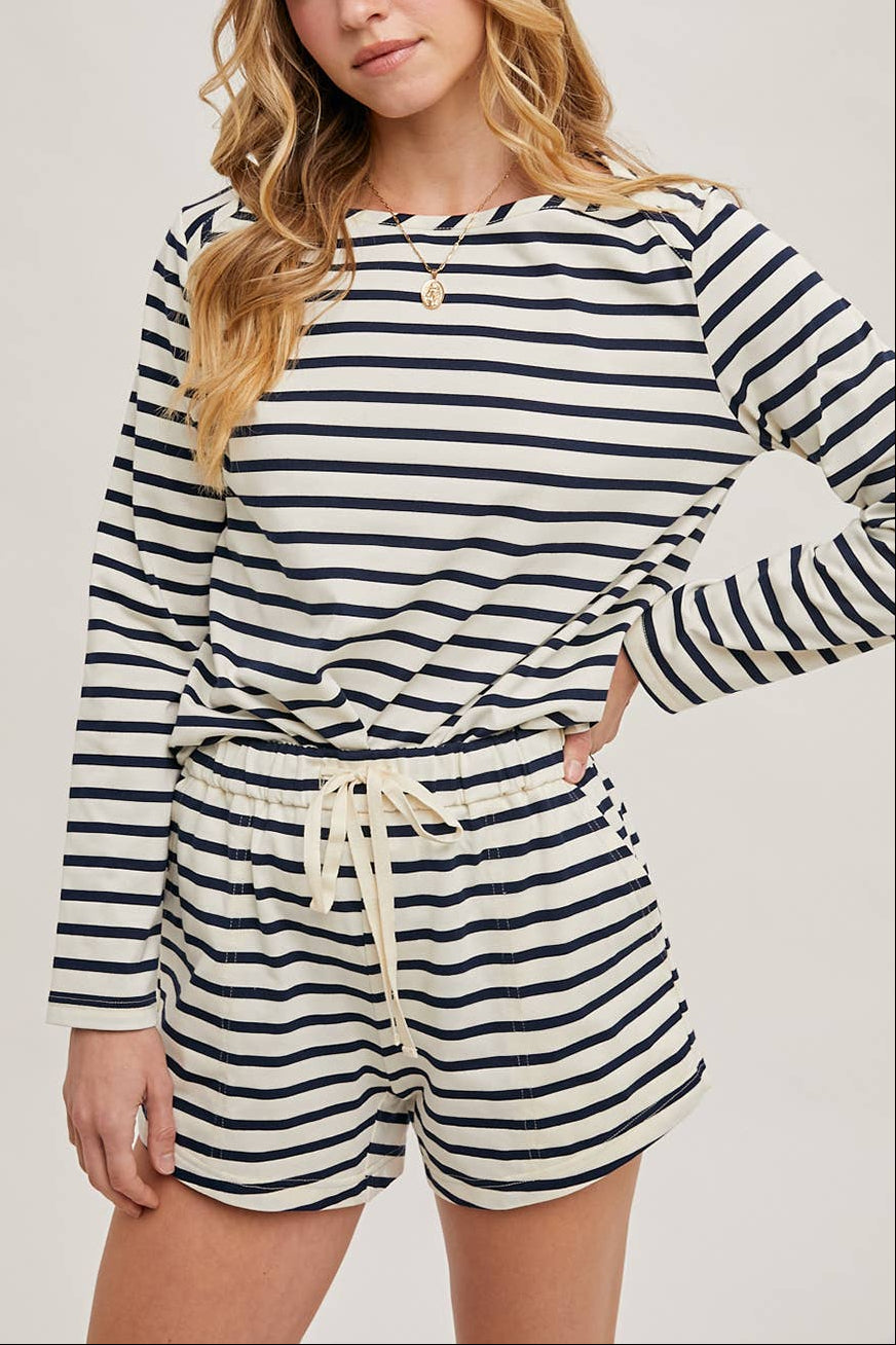 Woman wearing a navy and white striped longsleeve and shorts set on a plain background