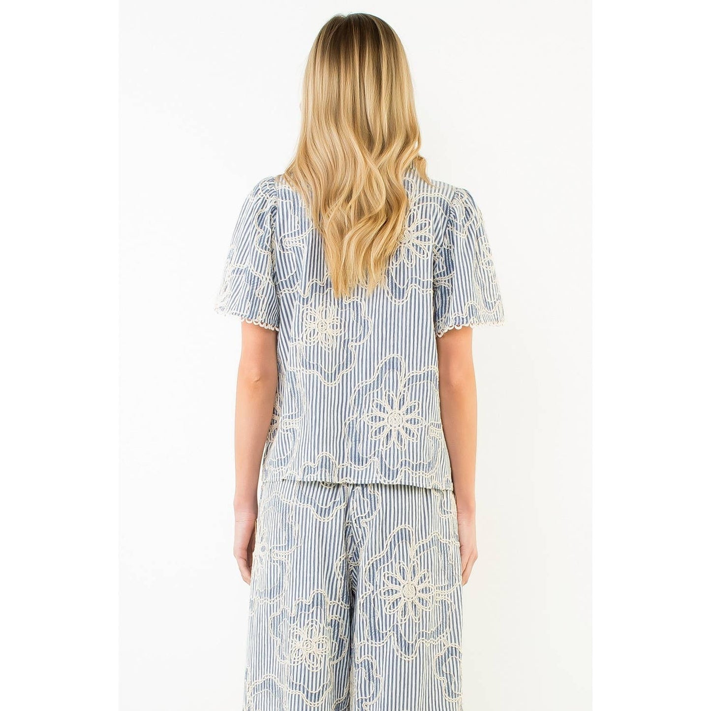 Back view of a woman wearing a blue and white patterned outfit on a white background