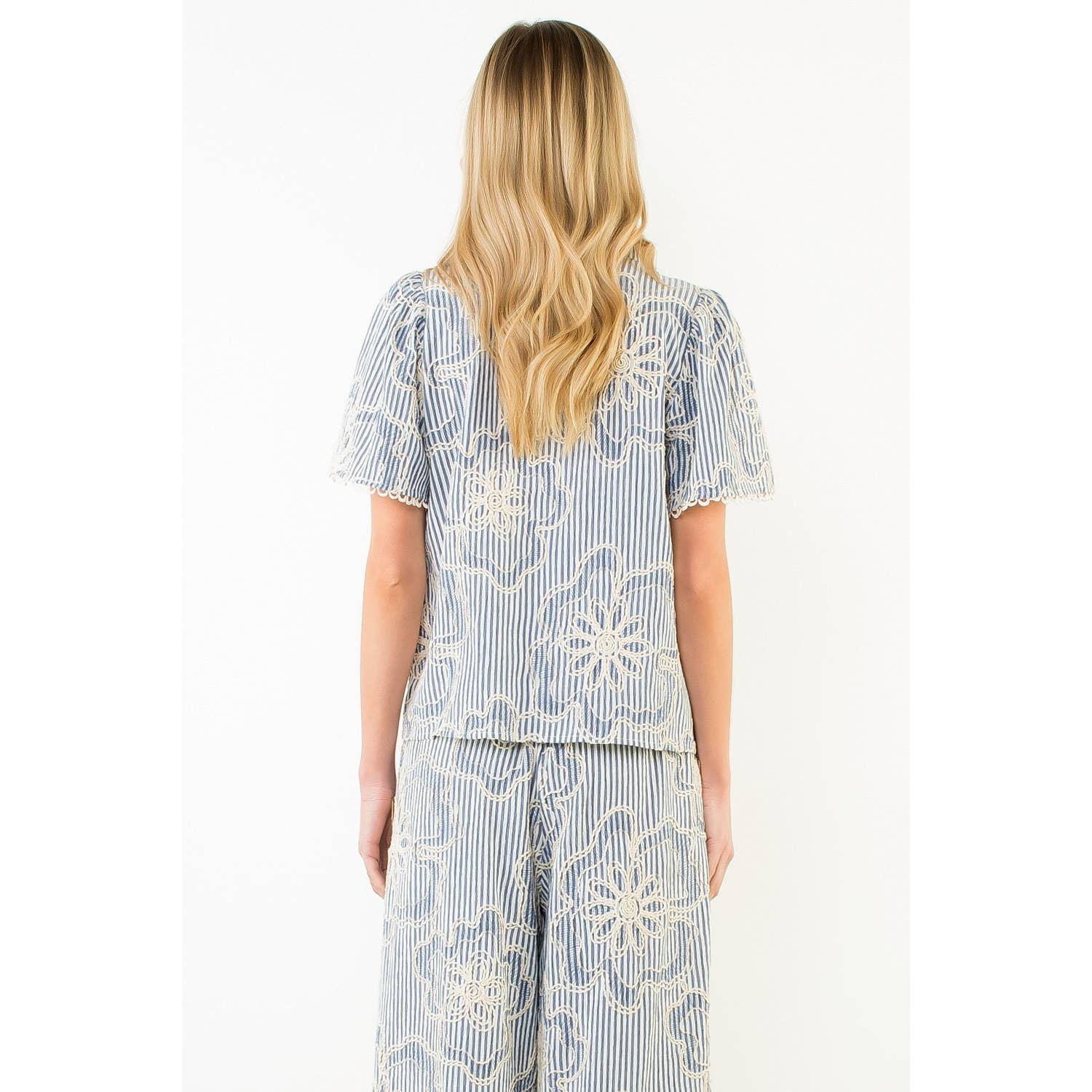 Back view of a woman wearing a blue and white patterned outfit on a white background