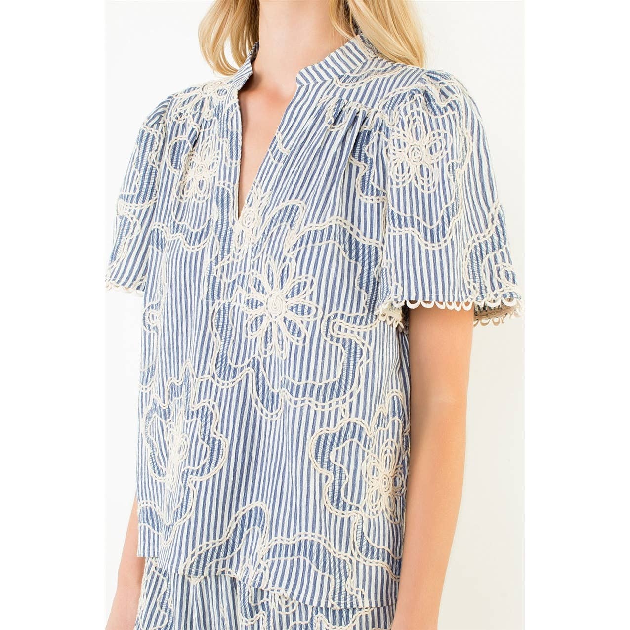 Woman wearing a blue and white striped dress with floral embroidery on a white background