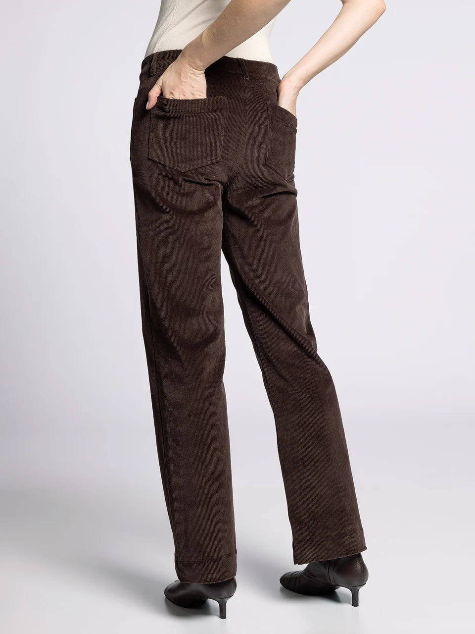 Brown corduroy pants worn by a person on a white background